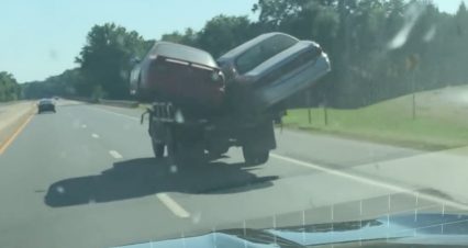 Cars Hang Over The Side As Dump Truck Driver Continues Down Highway